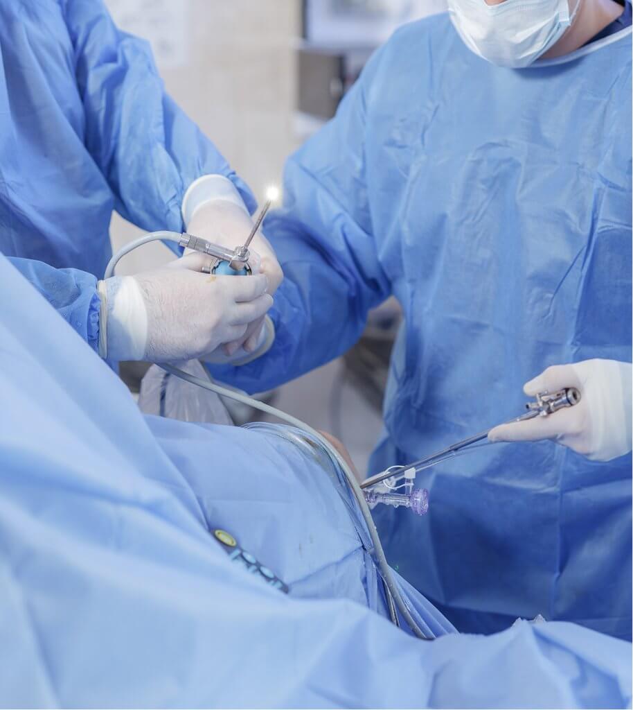 A surgical team in sterile gowns and gloves performs a minimally invasive laparoscopic procedure using specialized instruments at a Proliance Surgeons ambulatory surgical center