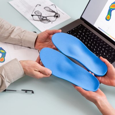 Female doctor orthopedist  presents new custom made insoles to a male patient in a clinic.   Feet recreation and orthotic medicine concept