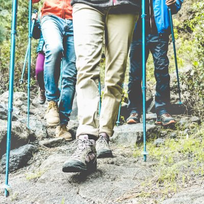 Legs view of people doing trekking excursion in mountain's path - Group of hikers walking in nature outdoor - Survival,travel and adventure concept - Focus on close-up foot