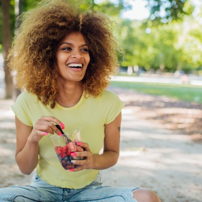 Beautiful girl resting in the park and eating fresh fruits