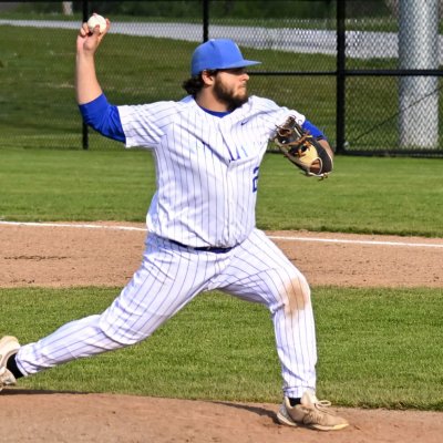 A high school baseball pitcher stepping off the rubber as he delivers his pitch to the plate