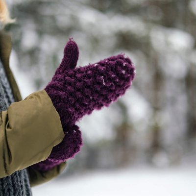 A side view of an unrecognizable Caucasian female using her mittens during cold winter days.